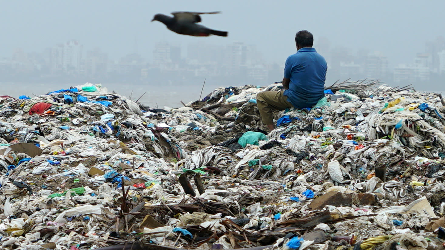 A man sits on a mountain of plastic garbage in Mumbai: India has pledged to eliminate disposable plastics within three years. (Photo by Akira Kodaka)